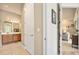 Hallway that leads to a bathroom vanity with double sinks and a view into the living room with a comfortable couch at 820 Aldenham Ln, Ormond Beach, FL 32174