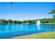 Scenic view of the lake with a fountain, surrounded by lush trees and landscaping on a bright sunny day at 820 Aldenham Ln, Ormond Beach, FL 32174