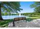 Peaceful park bench facing a serene lake with a fountain and lush trees under a clear blue sky at 820 Aldenham Ln, Ormond Beach, FL 32174