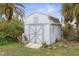 A backyard shot shows a charming shed with a blue exterior and double doors for ample storage at 5 Alamanda Dr, Ormond Beach, FL 32176