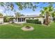 A spacious yard featuring a stone fire pit, mature palm trees, and a screened porch at 6680 Se 174Th Ln, Summerfield, FL 34491