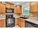 Well-lit kitchen featuring wooden cabinets, black appliances, and a window above the sink at 6680 Se 174Th Ln, Summerfield, FL 34491