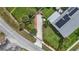 An aerial view of a well-maintained property featuring lush landscaping, solar panels, and a brick-lined driveway at 100 Lynnhurst Dr, Ormond Beach, FL 32176