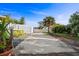 Long private driveway with white fence, lush tropical plants, and a fun yellow picnic table at 100 Lynnhurst Dr, Ormond Beach, FL 32176