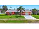 Charming single-story home with vibrant coral exterior, well-manicured lawn, and inviting curb appeal at 100 Lynnhurst Dr, Ormond Beach, FL 32176