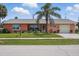 Attractive coral home with a well-kept lawn, mature palm trees, and inviting front yard at 100 Lynnhurst Dr, Ormond Beach, FL 32176