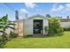 Backyard shed with an open door, lawnmower, plants, and gardening supplies on a well-maintained green lawn at 100 Lynnhurst Dr, Ormond Beach, FL 32176