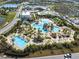 Aerial view of resort-style pool with tiki huts, lounge chairs, and lush landscaping in a planned community at 243 Island Breeze Ave, Daytona Beach, FL 32124