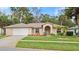 Inviting single-Gathering home with a well-kept lawn, attached two-car garage, and neutral-toned facade at 66 Old Sunbeam Dr, South Daytona, FL 32119