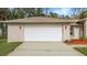 A close up of the 2 car garage door, clean driveway, manicured lawn and landscaping at 66 Old Sunbeam Dr, South Daytona, FL 32119