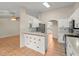 Open-concept kitchen featuring white cabinetry, stainless steel appliances, breakfast bar, and tile flooring at 66 Old Sunbeam Dr, South Daytona, FL 32119