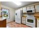 Functional kitchen featuring white appliances, wood cabinets and a window with patterned curtains at 1054 W Samms Ave, Port Orange, FL 32129