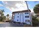 Multi-story white condo with a private parking lot and tropical trees around the building at 118 S Halifax Ave # 103, Daytona Beach, FL 32118