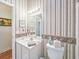 Bright bathroom featuring a white vanity, sink, and patterned wallpaper at 1187 Athlone Way, Ormond Beach, FL 32174