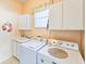 Cozy laundry room featuring a sink, cabinetry, and practical appliances at 1187 Athlone Way, Ormond Beach, FL 32174