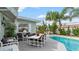 Inviting patio area next to a pool with ample seating and a table under a shady palm tree at 4 Water Oak Cir, Ormond Beach, FL 32176