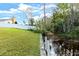 A lush green backyard with a serene canal, framed by a white fence for privacy and a tropical ambiance at 13 Twin River Dr, Ormond Beach, FL 32174