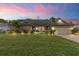 Charming single-story home at dusk featuring a stone accent wall, blue door and landscaped front yard at 13 Twin River Dr, Ormond Beach, FL 32174