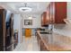 Galley kitchen featuring granite countertops, sleek black appliances, wood cabinets, and tile floors, perfect for cooking enthusiasts at 290 Birch Ave, Orange City, FL 32763