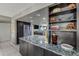Modern kitchen featuring stainless steel appliances, granite countertops, and dark wood cabinetry with open shelving at 3 Oceans West Blvd # 7C6, Daytona Beach Shores, FL 32118
