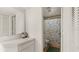 A well-lit bathroom with a vanity and a shower featuring a leafy patterned curtain at 11 Briggs Dr, Ormond Beach, FL 32176