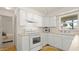 Functional kitchen featuring white cabinets and appliances, plus a view of the bedroom at 11 Briggs Dr, Ormond Beach, FL 32176