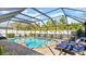 Backyard view of screened-in pool with blue lounge chairs and paver patio at 111 Heron Dunes Dr, Ormond Beach, FL 32176