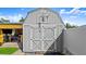 Charming gray storage shed with double doors and decorative trim, nestled near an outdoor tiki bar entertainment space at 111 Heron Dunes Dr, Ormond Beach, FL 32176