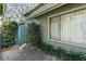 Landscaped exterior with large window and green wooden fence and gate at 128 Pine Cone Trl, Ormond Beach, FL 32174