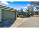 View of the detached single car garage and green wooden fence gate at the front of the townhome at 128 Pine Cone Trl, Ormond Beach, FL 32174