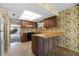 Vintage kitchen with wood cabinets, patterned wallpaper, and peninsula in need of updating at 128 Pine Cone Trl, Ormond Beach, FL 32174