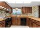 Vintage kitchen with wood cabinets, patterned wallpaper, and stainless steel appliances in need of updating at 128 Pine Cone Trl, Ormond Beach, FL 32174
