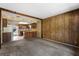Vintage living room with paneled walls, plush carpeting, and wood beam opens to kitchen in need of updating at 128 Pine Cone Trl, Ormond Beach, FL 32174