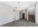 Open-concept living area with vintage chandelier, stairs and carpeted floors at 128 Pine Cone Trl, Ormond Beach, FL 32174