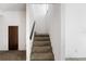 Carpeted staircase with white walls and a dark wooden door on the first floor at 128 Pine Cone Trl, Ormond Beach, FL 32174