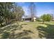 Large backyard with verdant grass, trees, and an inviting screened-in patio at 1432 Kinnard Cir, Ormond Beach, FL 32174