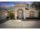 Elegant front entrance showcasing an arched doorway, arched windows, and manicured landscaping on a colorful evening at 1432 Kinnard Cir, Ormond Beach, FL 32174