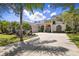 Elegant home featuring a large driveway, arched entryway, lush landscaping, and beautiful windows on a sunny day at 1432 Kinnard Cir, Ormond Beach, FL 32174