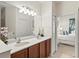 Bathroom featuring double sinks, wood cabinets, a large mirror, and a view to the bedroom at 1320 Hansberry Ln, Ormond Beach, FL 32174