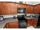 Wooden cabinets and black appliances and countertops in this kitchen at 1320 Hansberry Ln, Ormond Beach, FL 32174