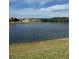 Scenic view of the community pond surrounded by lush green grass and homes in the distance under a sunny sky at 1320 Hansberry Ln, Ormond Beach, FL 32174