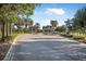 Entrance view with lush landscaping, paved road, mature trees, and an arched entrance at 187 Indian Wells Ave, Kissimmee, FL 34759