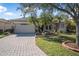 Well-maintained single-story home featuring a paver driveway, lush landscaping, and stone accents at 187 Indian Wells Ave, Kissimmee, FL 34759