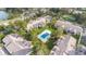 Overhead view of condominium buildings with a central swimming pool, grassy lawns, mature trees and parking at 1 Tomoka Oaks Blvd # 112, Ormond Beach, FL 32174