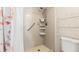 Shower with tile, showerhead, grab bar, and shelving unit adjacent to a toilet and shower curtain at 1 Tomoka Oaks Blvd # 112, Ormond Beach, FL 32174