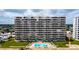 Exterior of the high-rise condominium with lush green lawns, palm trees, and a beautiful swimming pool at 1133 Ocean Shore Blvd # 302, Ormond Beach, FL 32176