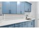 Laundry room featuring bright blue cabinets, quartz counters, and modern appliances at 2244 S Halifax Dr, Daytona Beach, FL 32118