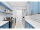 Laundry room featuring modern appliances, shelving and bright blue cabinets at 2244 S Halifax Dr, Daytona Beach, FL 32118