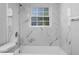 Updated bathroom with a marble-look tile surround, shower head, and window at 1011 Indian Oaks W, Daytona Beach, FL 32117