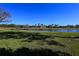 Scenic backyard view overlooking a serene pond and manicured green lawn under a clear blue sky at 1317 Dovercourt Ln, Ormond Beach, FL 32174